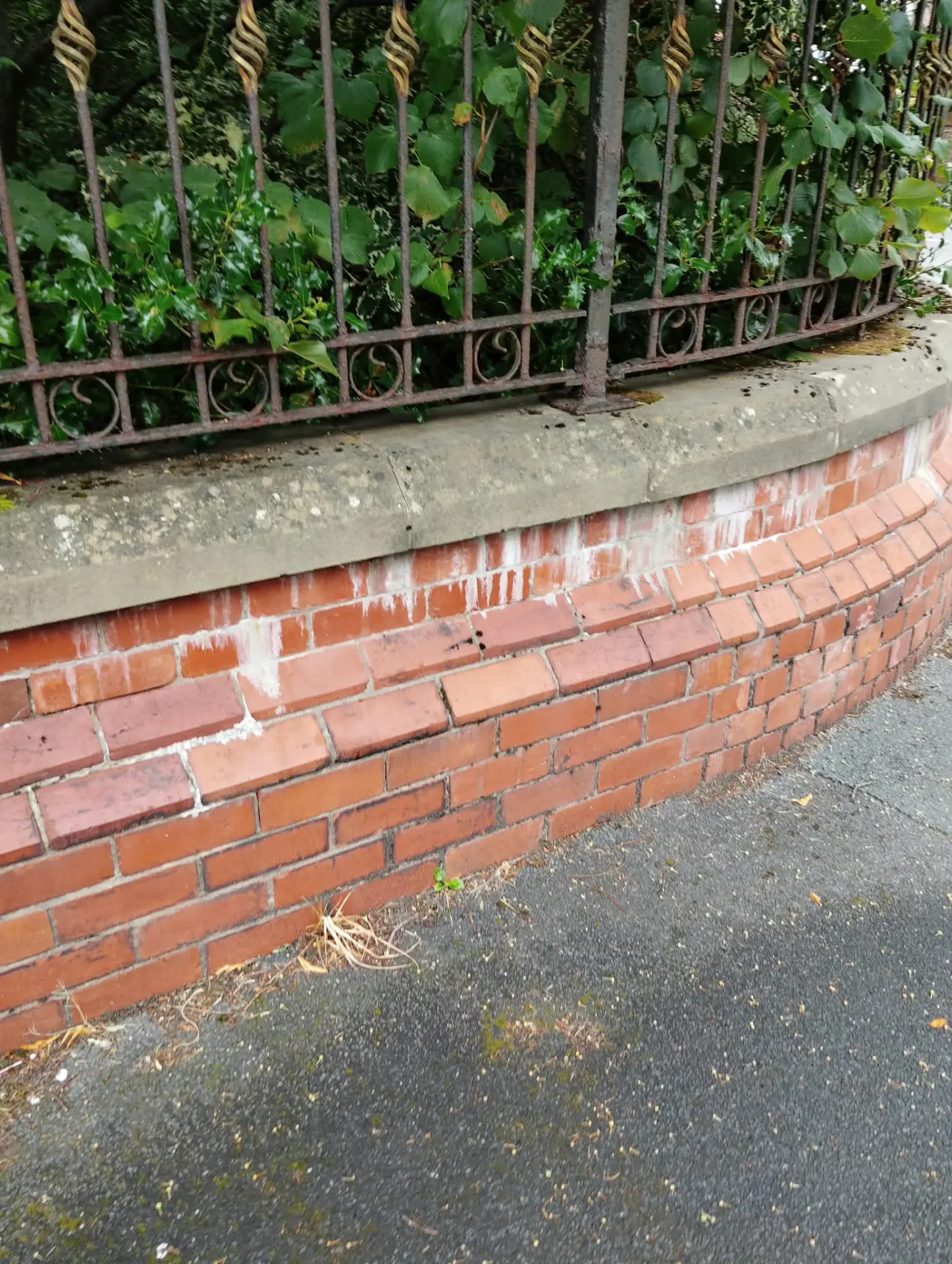 Red brick boundary wall before acid cleaning, showing lime bloom and white staining