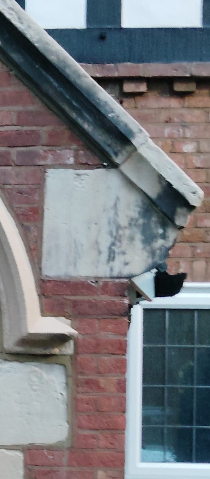 Soiled stone gable coping and blackened masonry detail before conservation cleaning