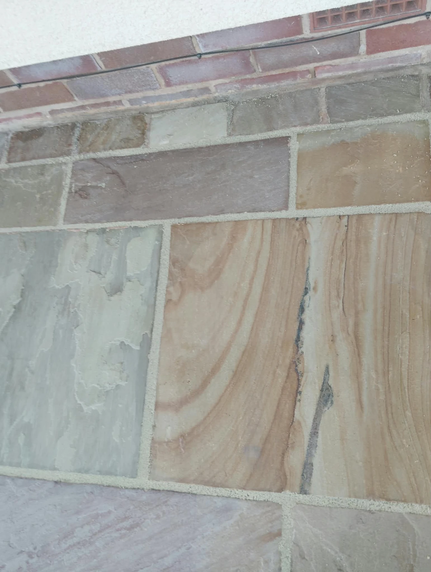 Detail of restored sandstone paving with crisp new pointing against brickwork