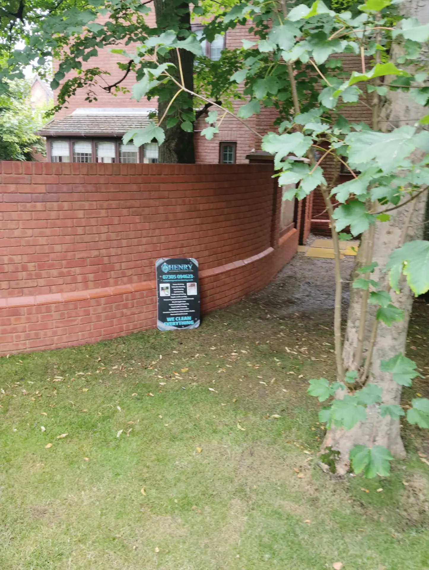 Long curved brick garden wall cleaned and brightened beside a lawn