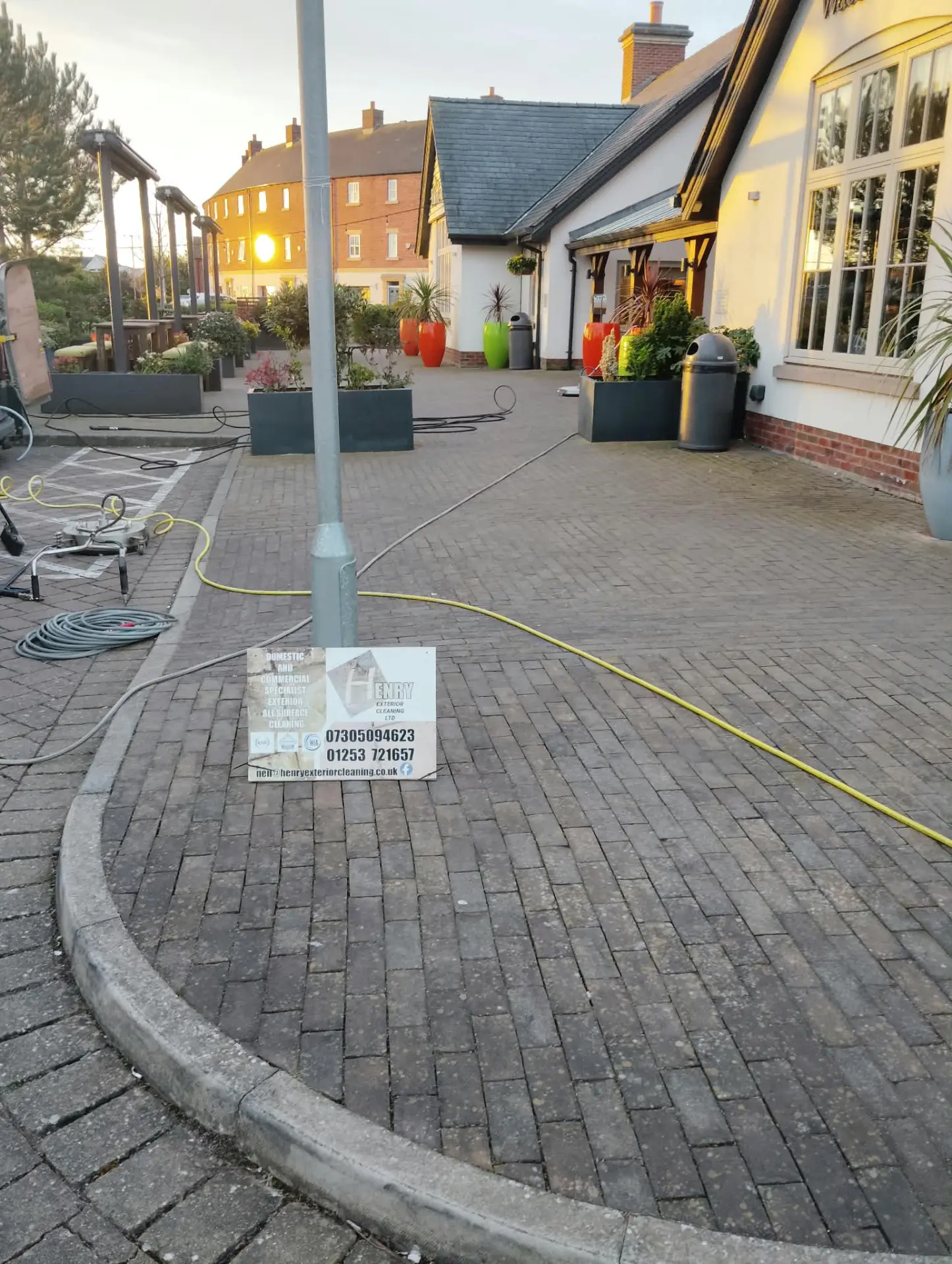 Clay paving being deep cleaned at dusk with rotary surface cleaner and hoses in place