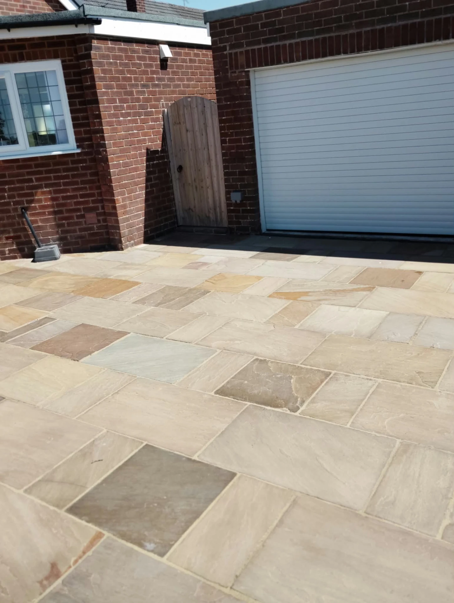 Restored buff sandstone driveway in front of a red brick garage