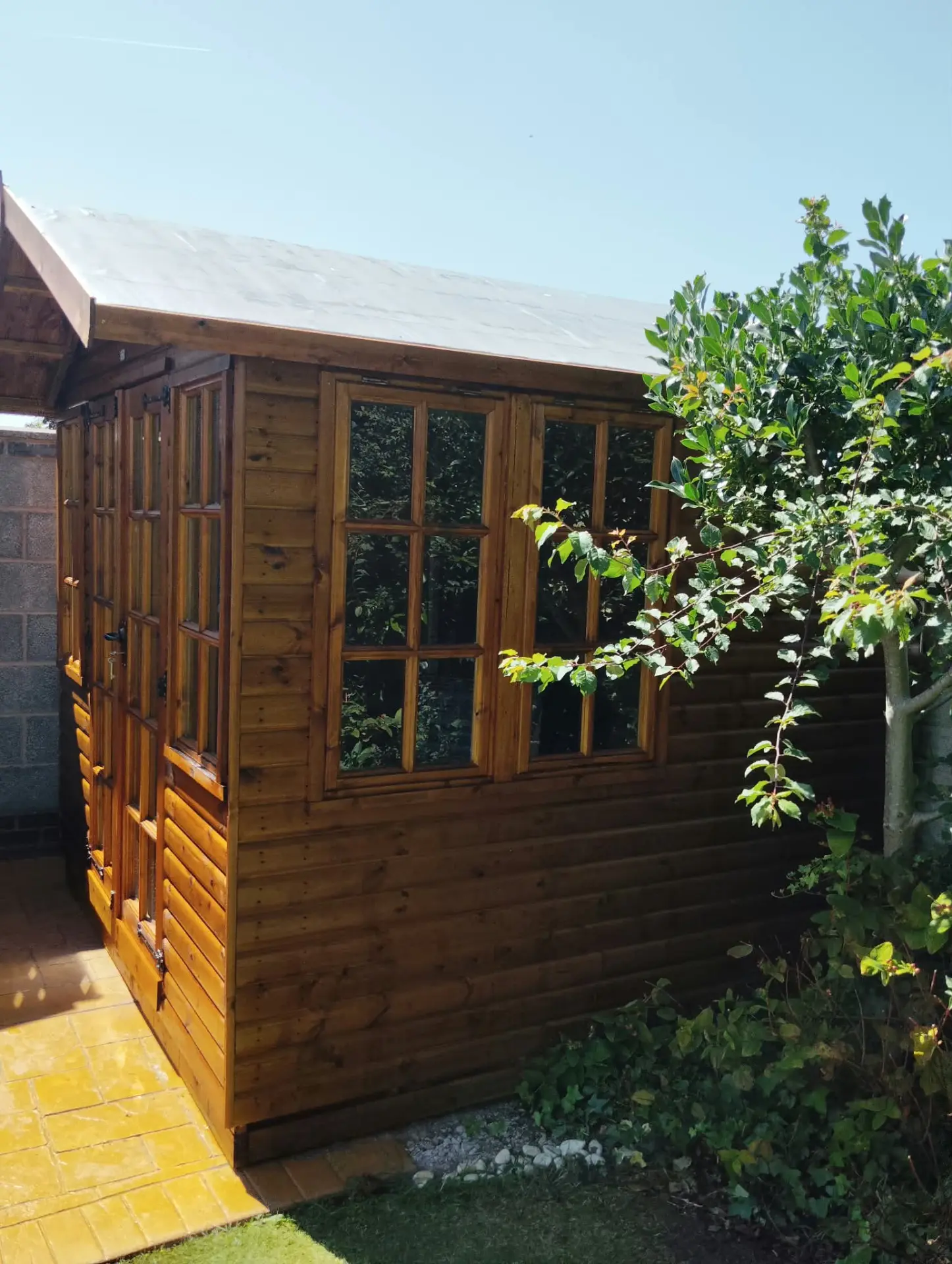 Side elevation of a garden summerhouse after softwash cleaning and timber treatment