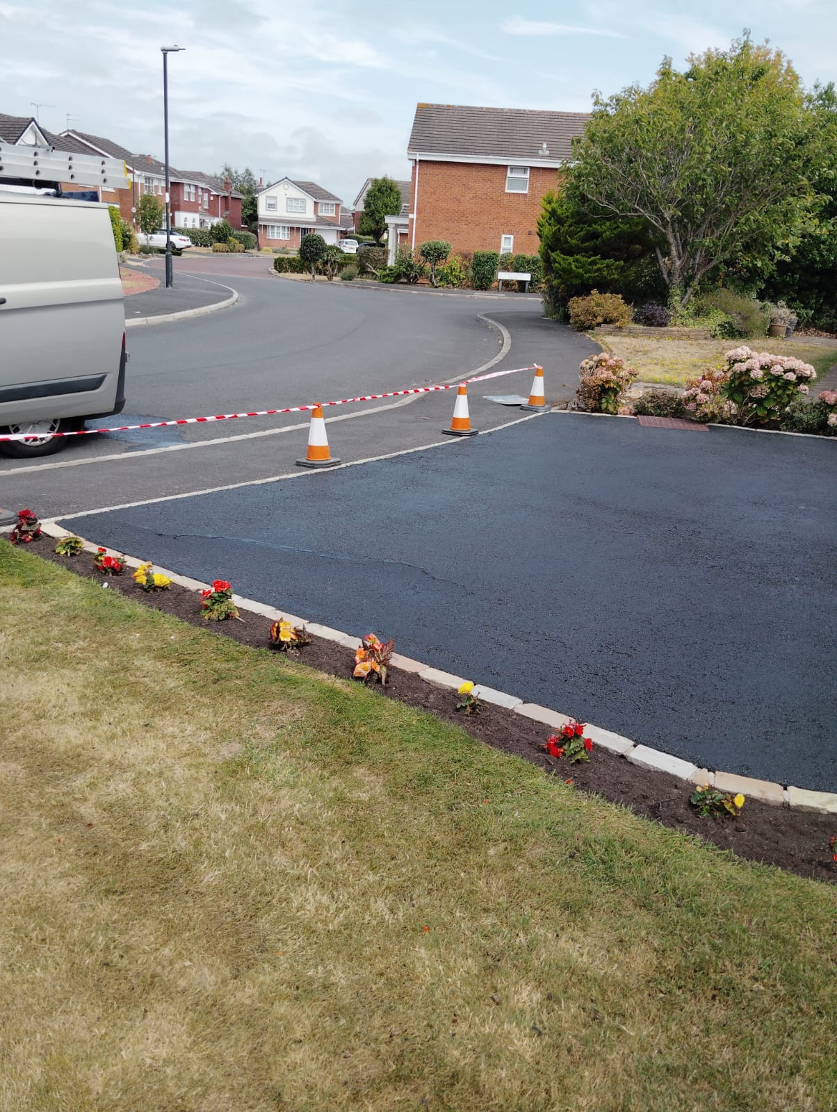 Tarmac driveway cordoned with cones and tape while the restorer dries