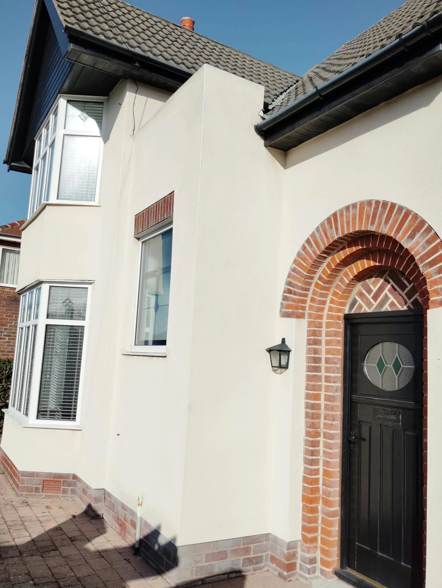 Cream rendered elevation and brick archway after render cleaning