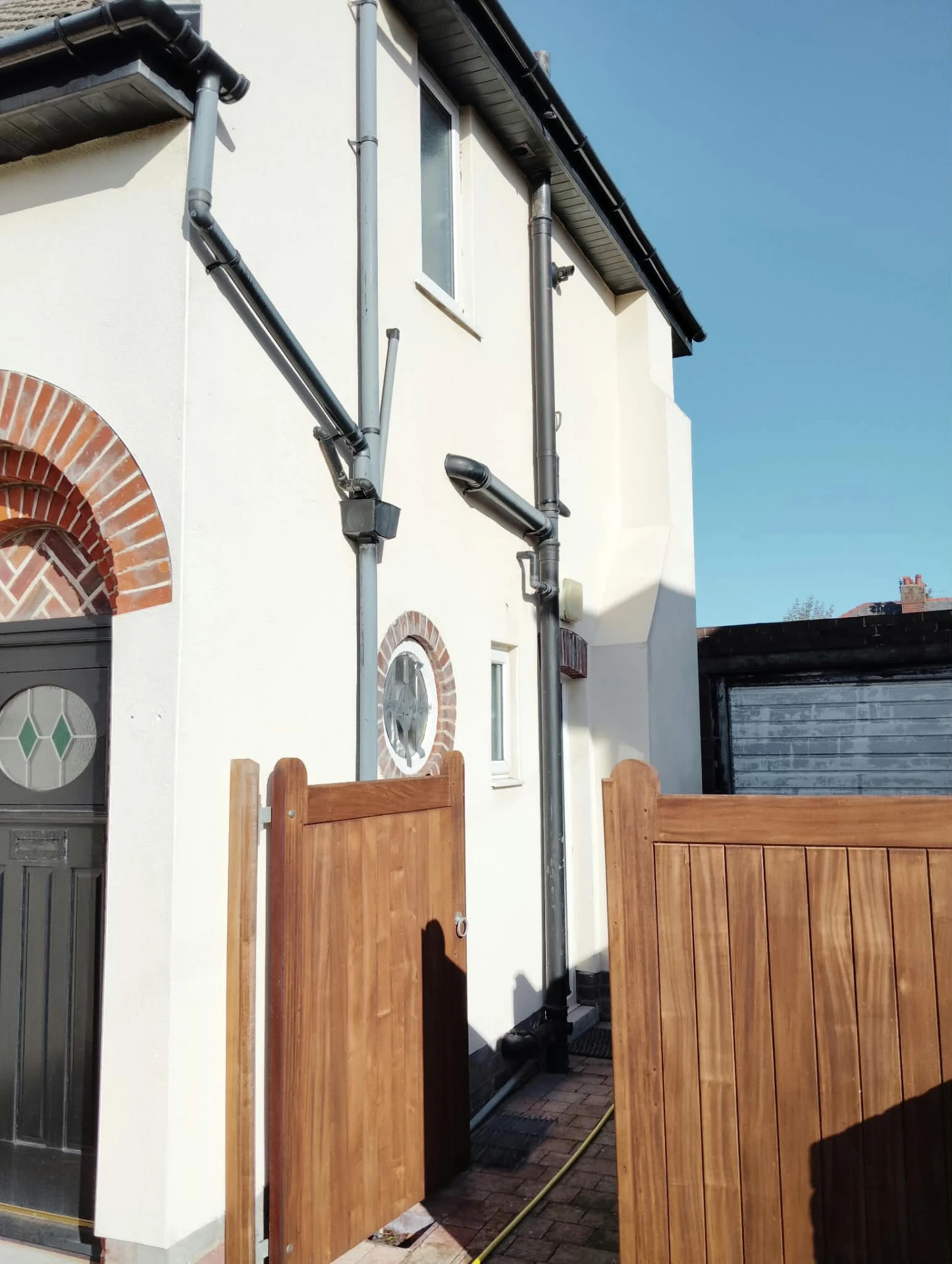 Cleaned white render and downpipes on the side elevation of a house