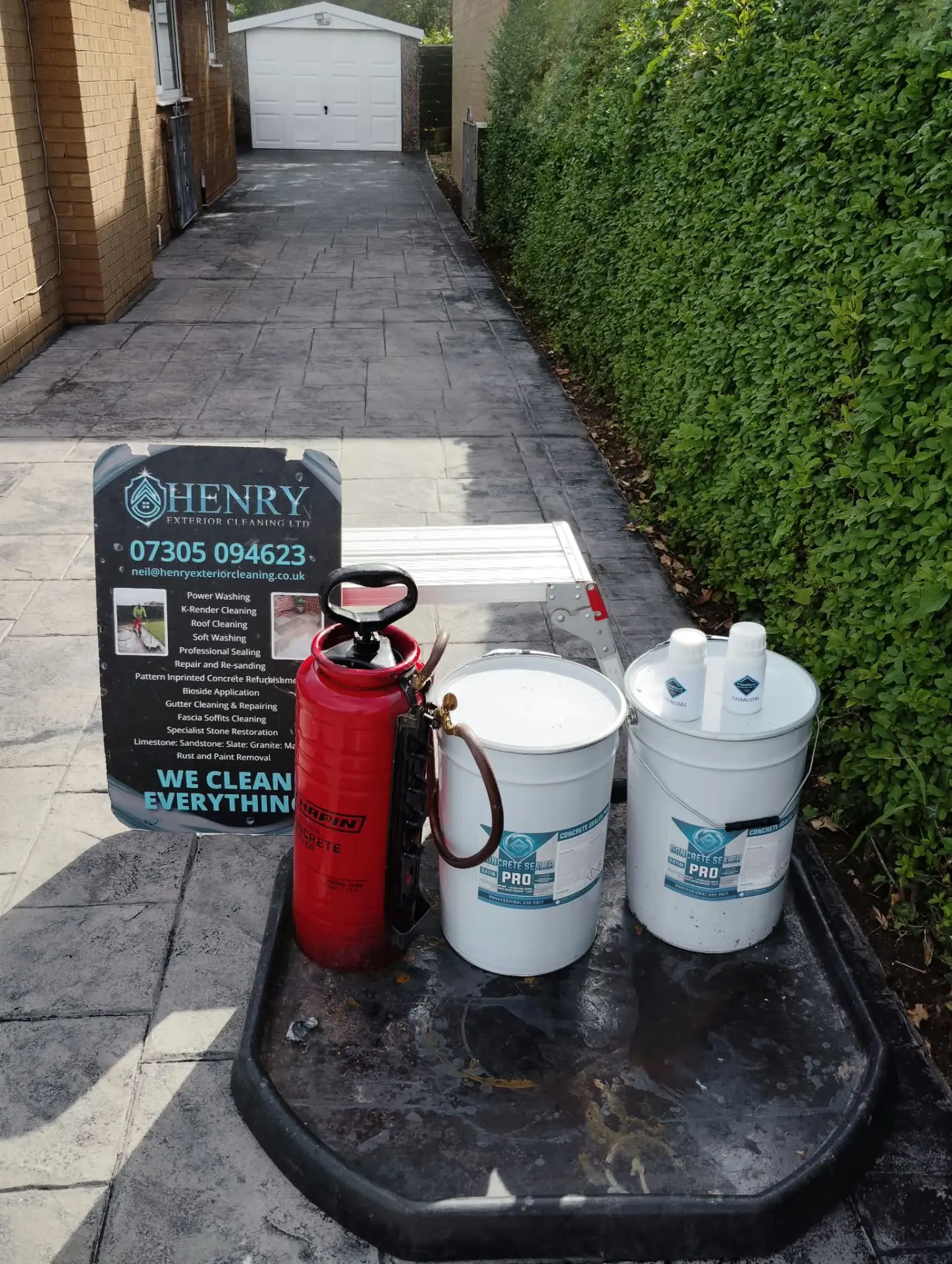 Concrete sealer and biocide equipment set up on a pattern imprinted driveway