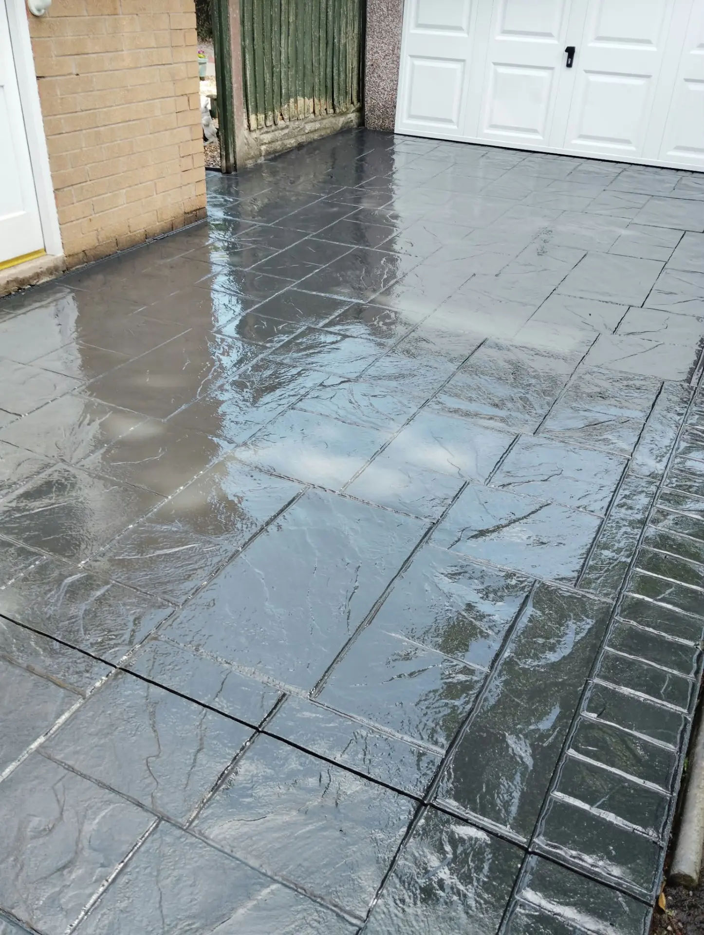 Freshly sealed pattern imprinted concrete driveway with a high-gloss wet finish