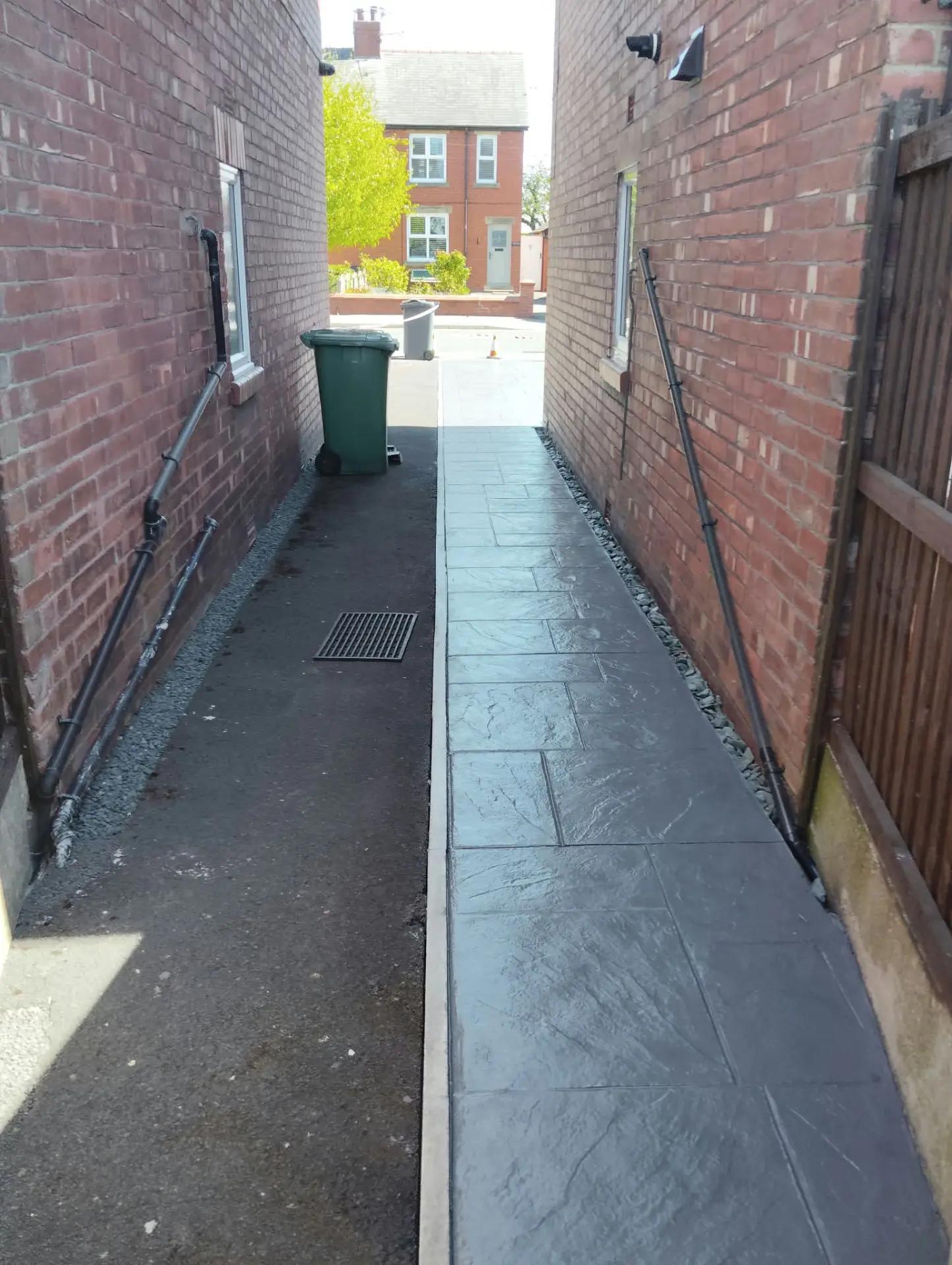 Charcoal pattern imprinted concrete side path between two brick properties
