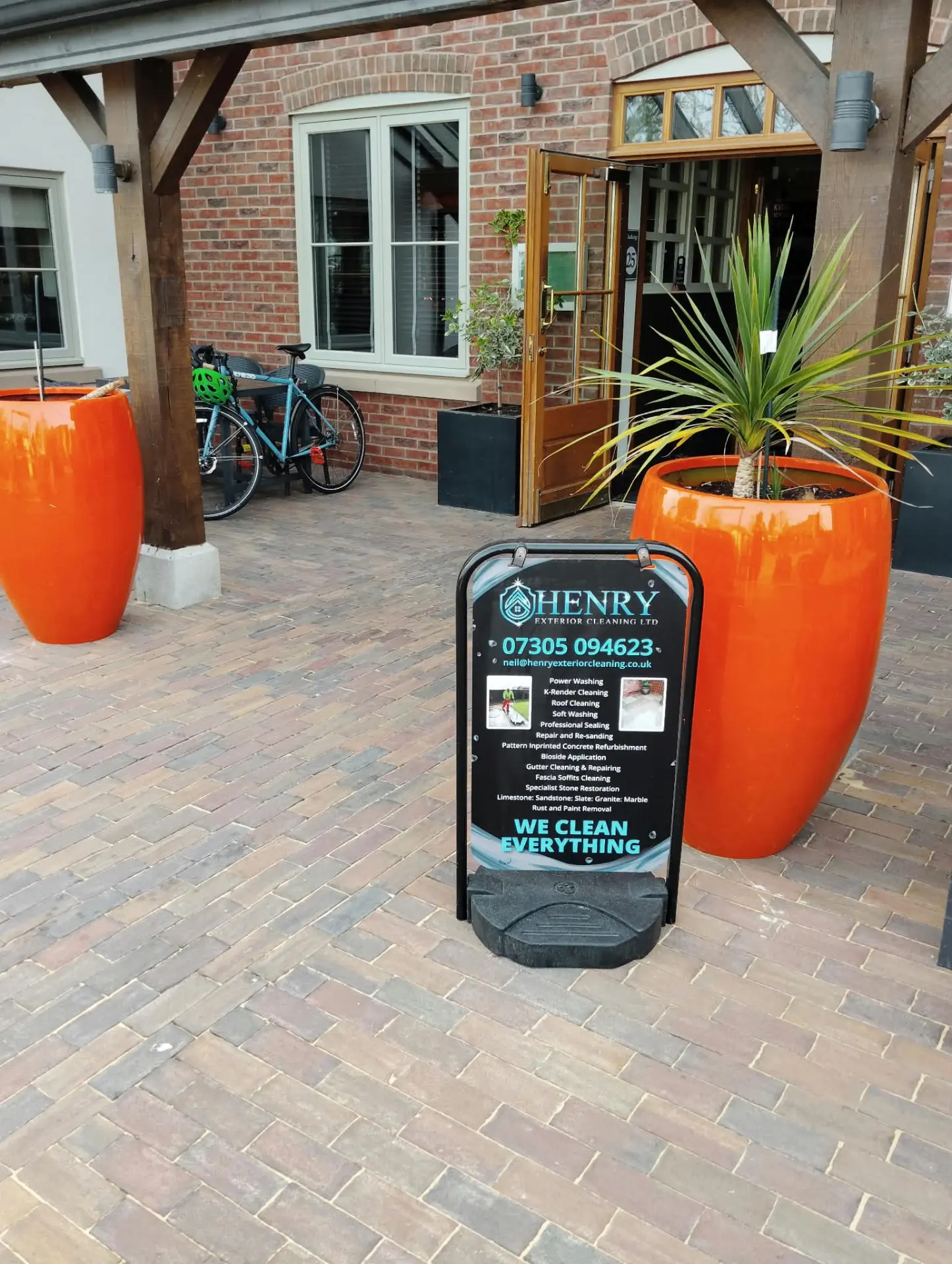 Restored clay paving under a timber canopy with Henry Exterior Cleaning site board