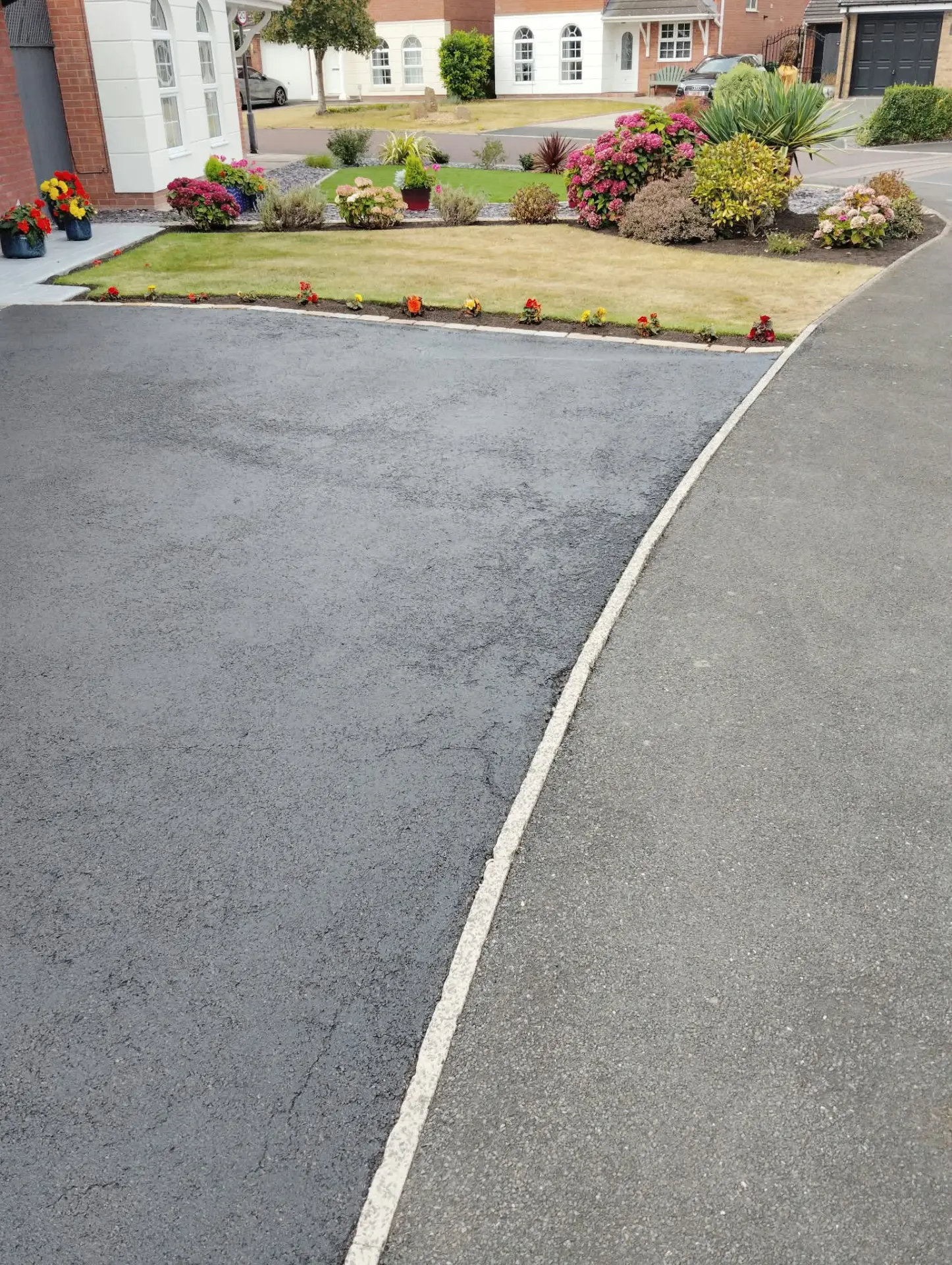 Half-restored tarmac driveway showing the deep black finish against the faded original surface