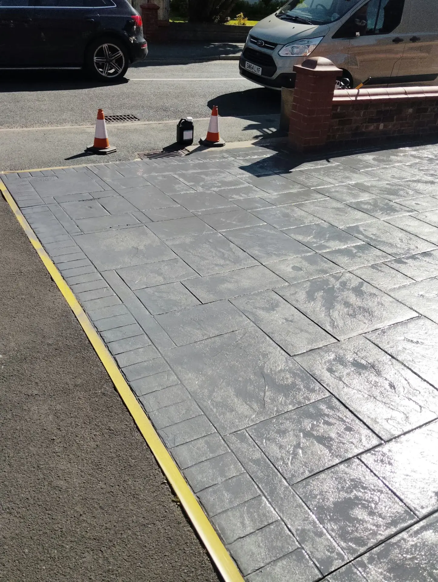 Large grey pattern imprinted concrete driveway resealed and cordoned off to cure