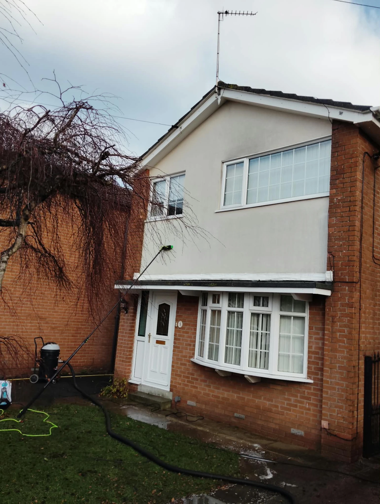 Render cleaning in progress on a front elevation with equipment on the lawn